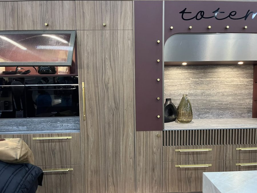 Kitchen cabinetry in warm oak and deep oxblood with a fluted base panel and integrated oven