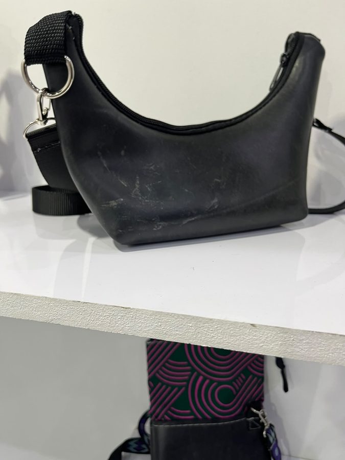 Slouchy black leather handbag on a white shelf, with a patterned lining visible beneath