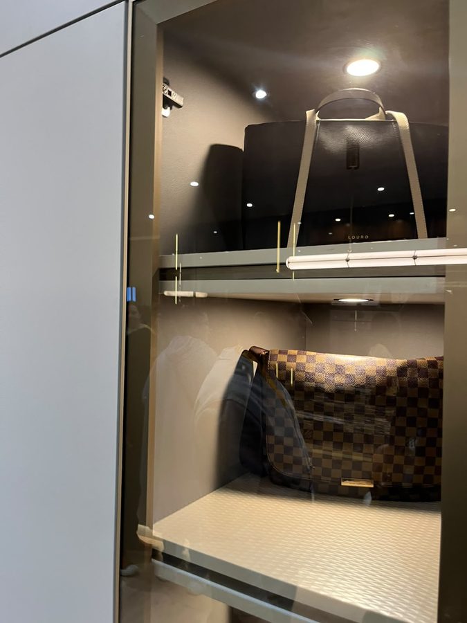 Wardrobe interior joinery with a brass hanging rail and integrated shelf lighting